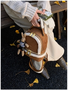 Close-up of brown suede mini backpack with white faux fur trim and gold zipper details