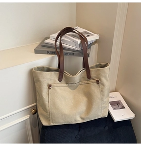 Detail of khaki canvas tote bag with brown leather straps and front pocket reinforcement