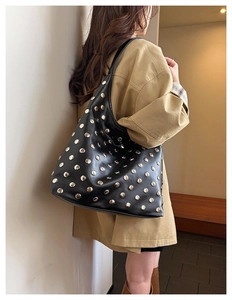 Detail of vintage black leather hobo bag featuring decorative silver metal rivets and wide strap