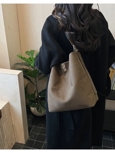Detail of the silver rotating metal lock and matte texture on a large brown bucket bag