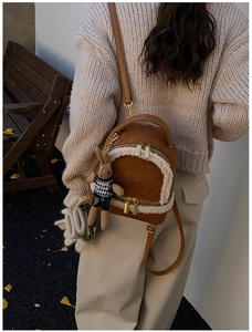 Rear view of a mini brown faux suede backpack with white shearling trim and rabbit charm