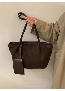 Detail of a large dark brown tote bag with a matching small zipper pouch on a trench coat