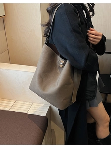 Close-up of brown matte suede bucket bag showing the silver twist lock and wide strap
