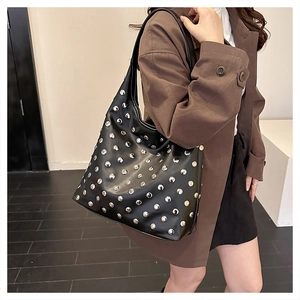 Close-up of black hobo bag featuring silver studded matrix and wide shoulder strap