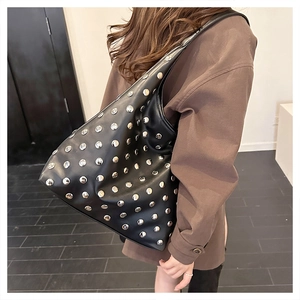 Model showcasing a vintage black shoulder bag with silver studs and a wide strap style