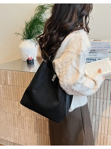 Close-up of black suede bucket bag showing the silver metal twist lock and soft texture