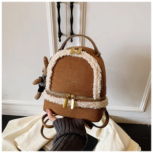 Detail view of mini brown faux suede backpack with white faux fur trim and rabbit charm