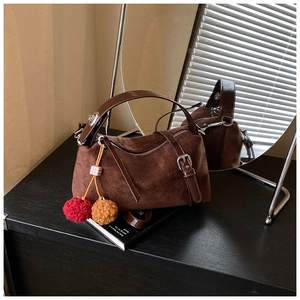 Detail of suede pillow bag with leather handles, silver hardware, and colorful charms