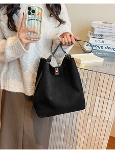 Detail of matte black bucket bag with metallic twist lock and versatile shoulder strap