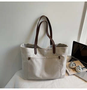 Close-up of vintage canvas tote bag with brown leather handles and bronze rivets