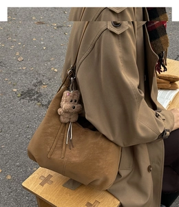 Gros plan sur un sac cabas vintage marron en daim avec un pendentif ours en peluche mignon