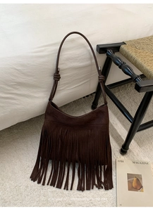 Detail of dark brown suede bag with long tassels and knotted strap in retro style