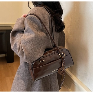 Gros plan d'un sac oreiller en cuir marron avec logo imprimé et pendentif rond chic