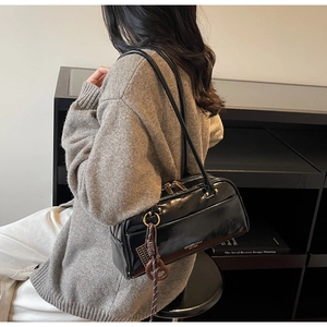 Détail du sac sous l'aisselle noir brillant avec breloque boulier en bois et fines lanières