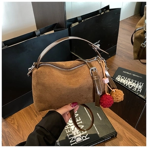 Brown faux suede pillow bag detail featuring dark leather handles and furry charms