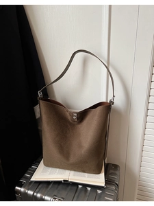 Close-up of brown suede bucket bag featuring high-quality silver magnetic clasp detail
