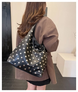 Detail of a vintage black leather tote bag with dense silver rivet stud embellishments