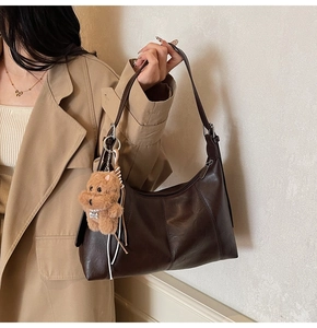Detail of retro dark brown leather underarm bag with a cute teddy dog plush charm