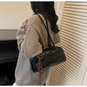 Detailed view of a vintage black rectangular shoulder bag with chic silver hardware and charm
