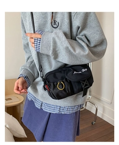 Detail view of black utility crossbody bag with flap buckle and front mesh pocket
