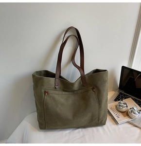Detail of olive green canvas tote bag showing brown leather handles and front pocket