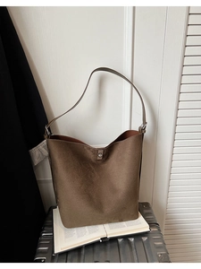 Close-up of brown suede bucket bag featuring a silver metal twist lock and soft texture