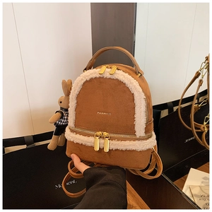 Close-up of brown suede mini backpack with white faux fur trim and cute rabbit charm