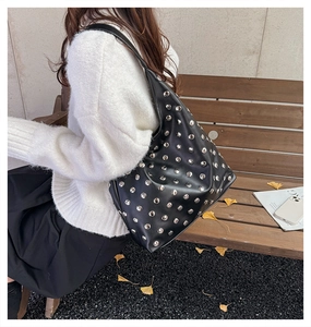 Close-up of vintage black rivet hobo bag with silver studs and soft PU leather texture