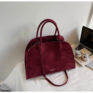 Close-up of large burgundy suede tote bag with brand logo and daily office accessories