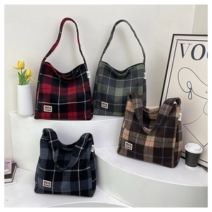 Detail of four colorful checkered flannel tote bags with bear patches on display stands