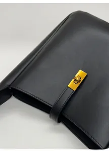 Detail view of the black soft leather bucket bag featuring a premium gold twist lock closure