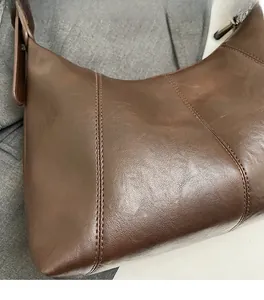 Close-up of brown leather hobo bag showing vertical stitching and soft grain texture