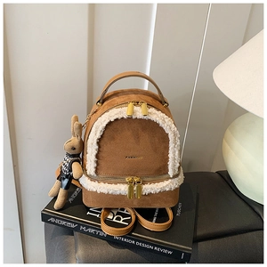 Close-up of brown suede mini backpack featuring white plush trim and a cute rabbit charm