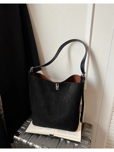 Close-up of black matte bucket bag with contrasting reddish-brown interior and metal clasp