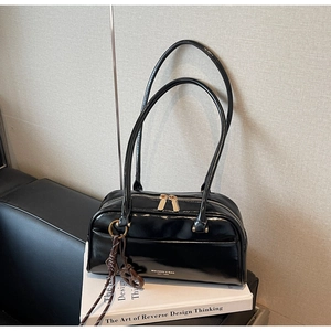 Détail du sac oreiller en cuir verni noir avec lettrage blanc et zips dorés doubles