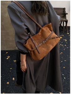Détail du sac fourre-tout en daim marron avec lanières en cuir et boucles argentées en automne
