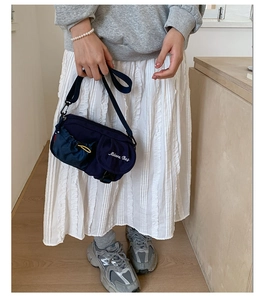 Detail of navy nylon crossbody bag with yellow drawstring pocket and Modern Bag embroidery