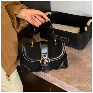Dettaglio della borsa a sella vintage nera con fibbia dorata e patchwork in camoscio