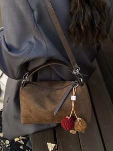 Minimalist brown suede oversized pillow bag with colorful pom-poms on long strap