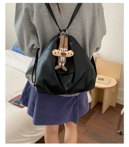 Detail of black vintage backpack with soft leather texture and cute plush bunny charm