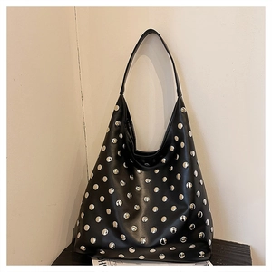 Detailed view of black leather hobo bag with silver metal rivets and wide shoulder strap