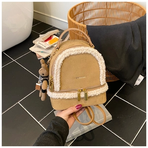 Detail of khaki suede mini backpack with white faux fur trim and cute rabbit pendant