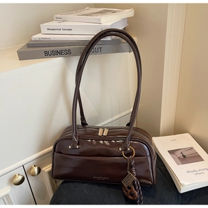 Détail du sac oreiller en cuir marron foncé brillant avec logo doré et pendentif