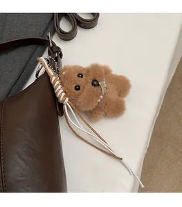 Detail of brown plush puppy bag charm with pearl necklace and golden bone tag decoration