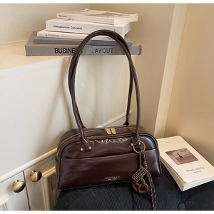 Détail du sac polochon marron brillant avec fines bandoulières et logo métallique