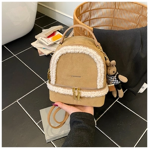 Detail shot of beige suede mini backpack with white faux fur trim and golden zippers