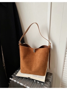 Detail of a brown matte bucket bag showing the metal twist lock on a vintage suede surface