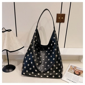 Detail of black leather hobo bag with silver rivet studs on a white table background
