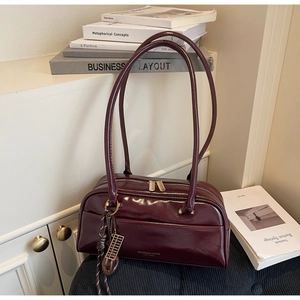 Détail du sac oreiller en cuir verni bordeaux avec pendentif boulier et double zip