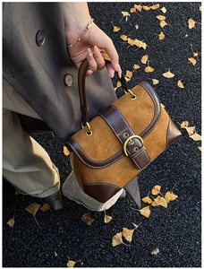 Detail of retro suede patchwork saddle bag with metal buckle and contrast stitching